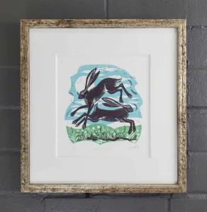 A framed picture of two animals jumping in the air.