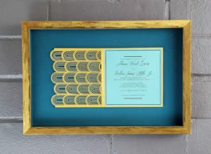 A framed invitation with a gold frame and blue background.