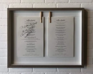 A framed menu with two clothespins attached to it.