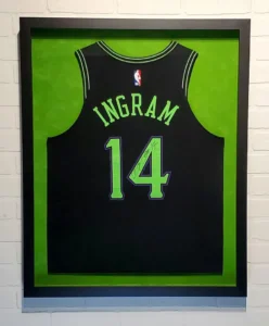 A framed jersey is displayed in front of a brick wall.
