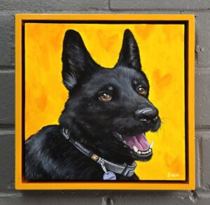 Dirk Hays Painting of a black german shepherd 'smiling' for the camera. The dog has golden brown eyes and has an black/grey collar peeking from under her fur. She is on a schoolbus yellow background with soft ephemeral hearts in a deeper color. The piece is framed in a schoolbus yellow floater frame that is hand painted.