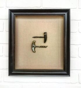 A picture frame with two pairs of scissors stuck in it.
