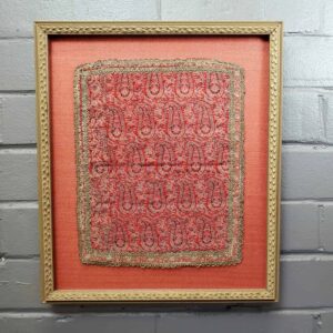 A framed picture of a red and gold pattern.