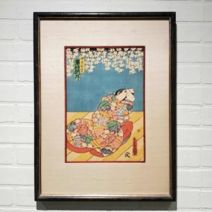 A framed picture of a woman sitting on the ground.